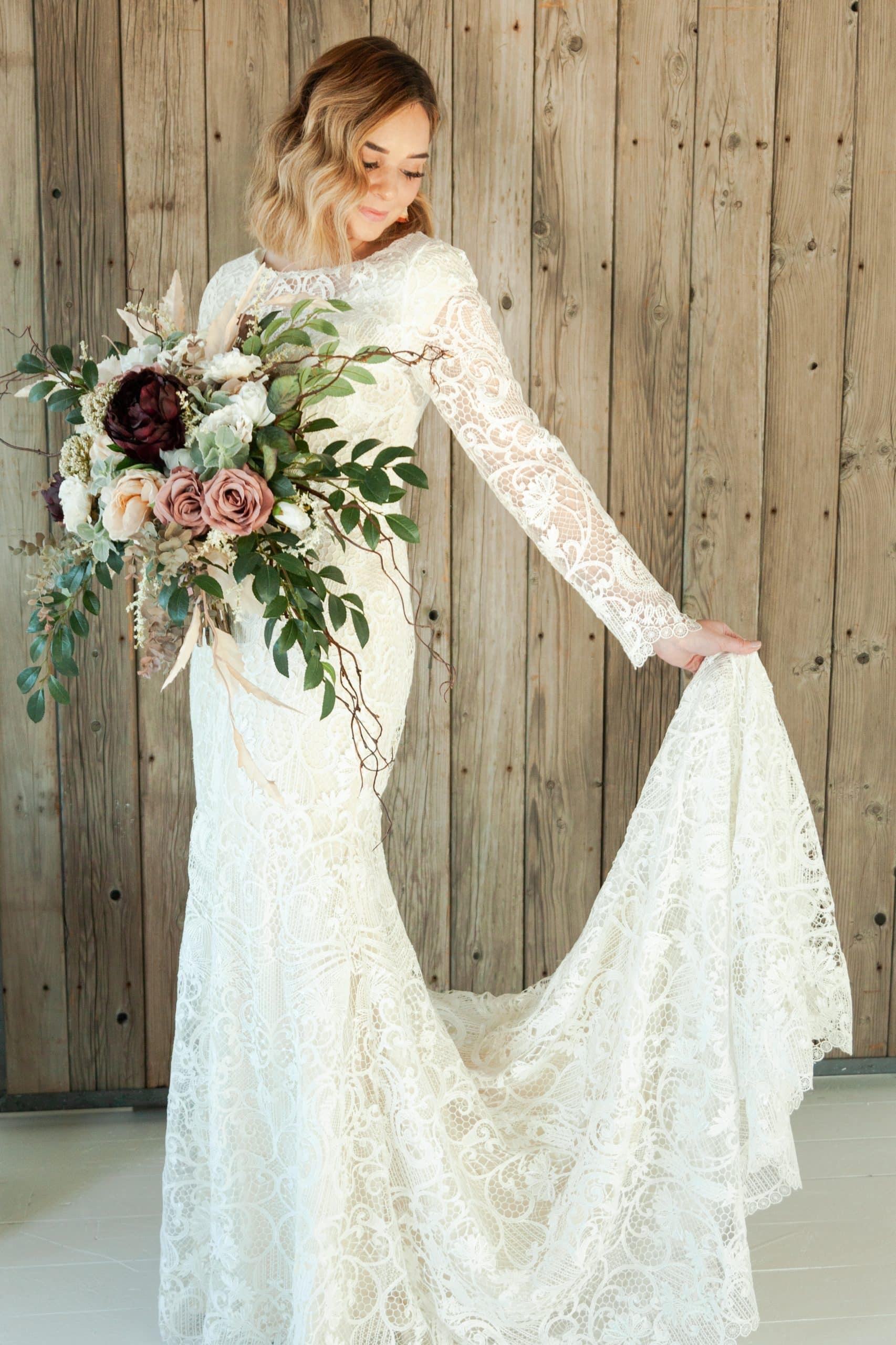 A bridge wearing a modest bridal gown while holding a bouquet of flowers